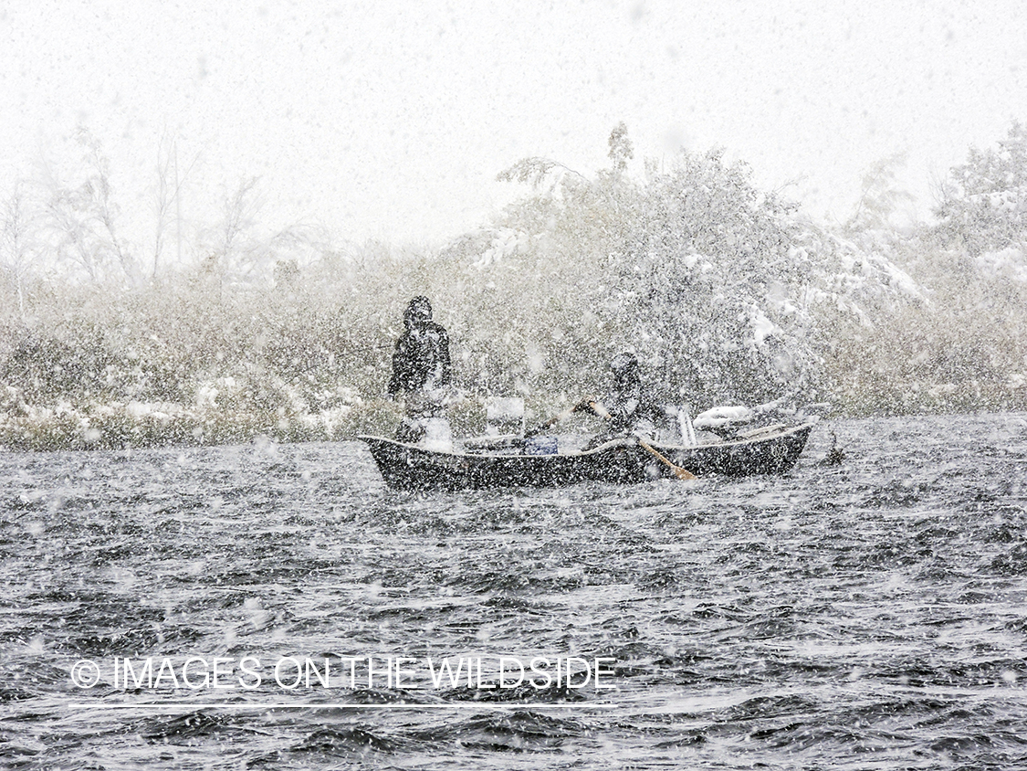 Flyfisherman in drift boat during snow storm.