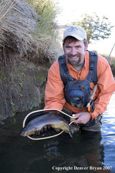 Flyfisherman holding brown trout.