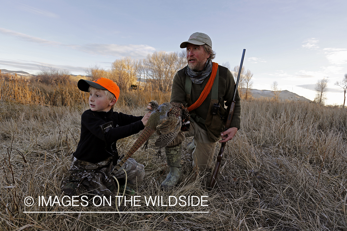 Father and son pheasant hunters with bagged pheasant. 