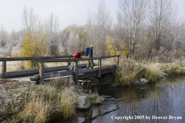 Flyfishermen crossing foot bridge.