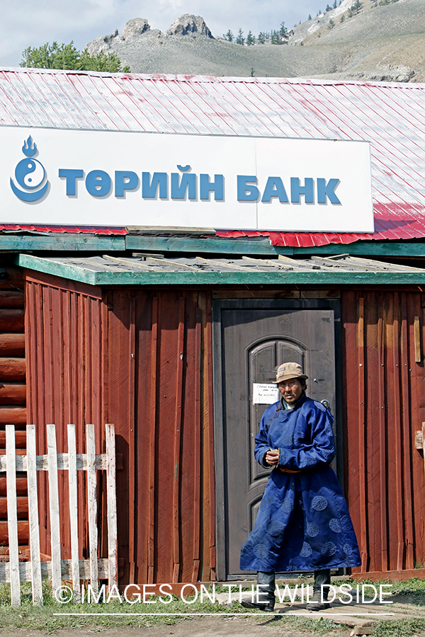 Mongolian man in traditional garment leaving small town bank.