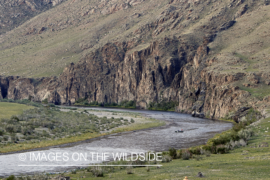 Flyfisherman on drift boat, floating Delger River, Mongolia.