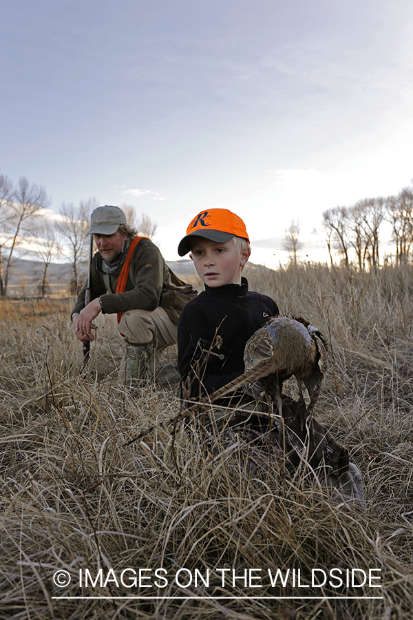 Father and son pheasant hunters with bagged pheasant. 