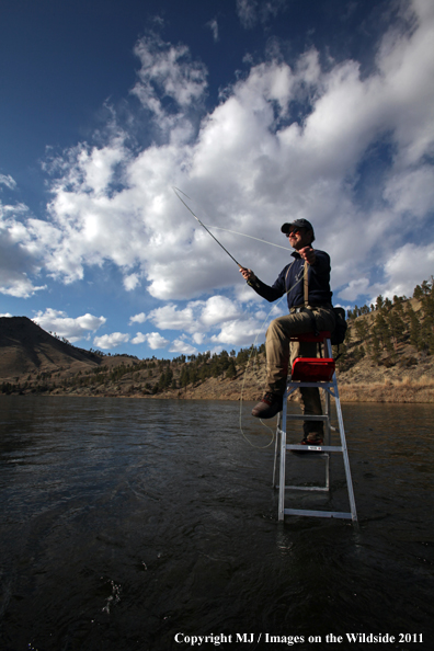 Flyfisherman casting from ladder in middle of river.