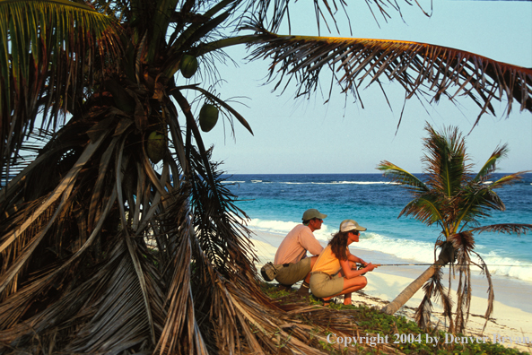 Saltwater flyfishing couple look for fish from beach.