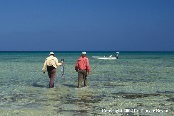 Saltwater flyfishermen walking towards boat with barracuda.