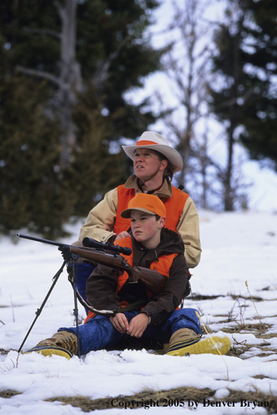 Father and son hunters big game hunting in a field in winter.