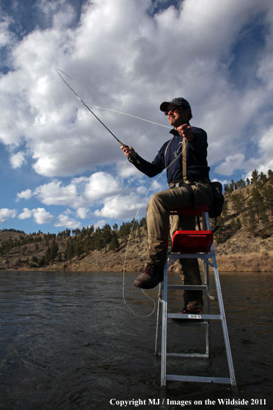 Flyfisherman casting from ladder in middle of river.