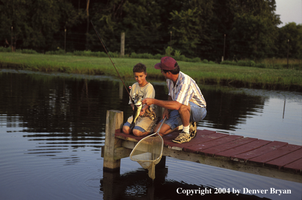 Man helping spincast fishing boy