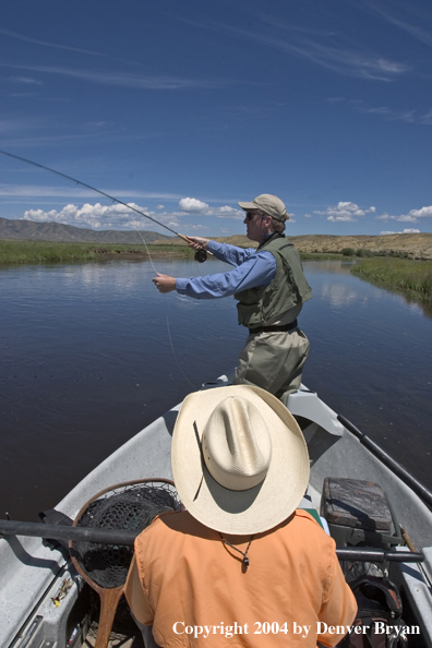 Flyfishermen fishing river from drift boat.  Summer.