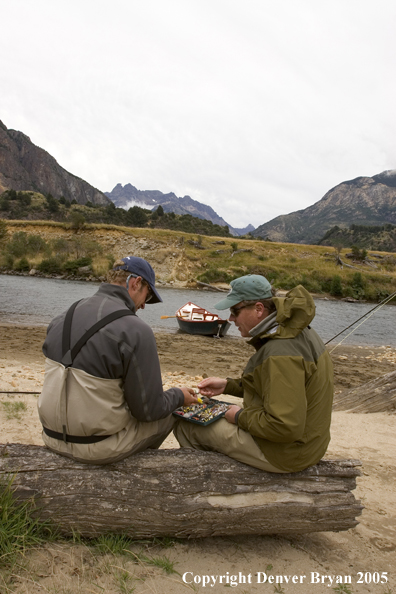 Flyfishermen choosing flies.  Driftboat in background.