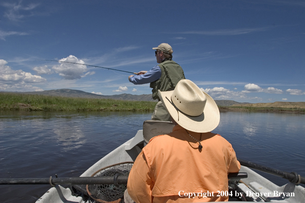 Flyfishermen fishing river from drift boat.  Summer.