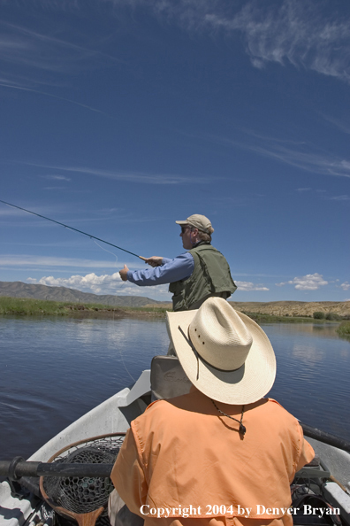 Flyfishermen fishing river from drift boat.  Summer.