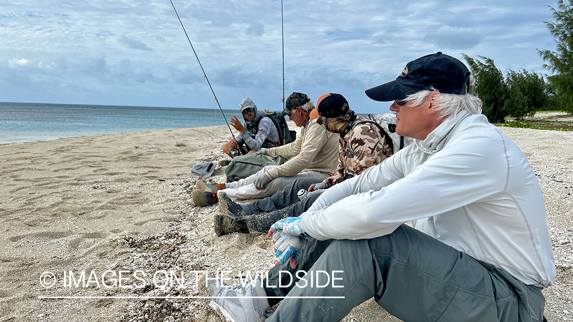 Flyfishermen sitting on beach.