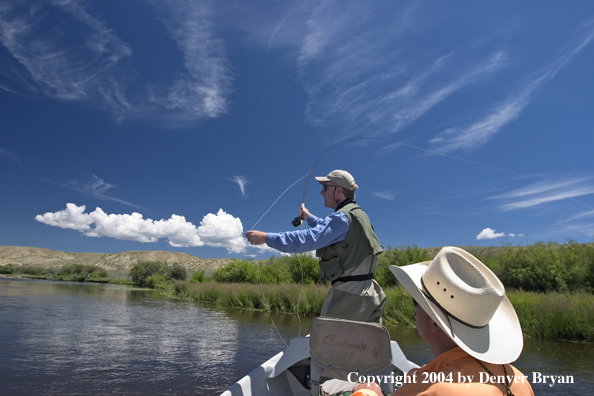 Flyfishermen fishing river from drift boat.  Summer.