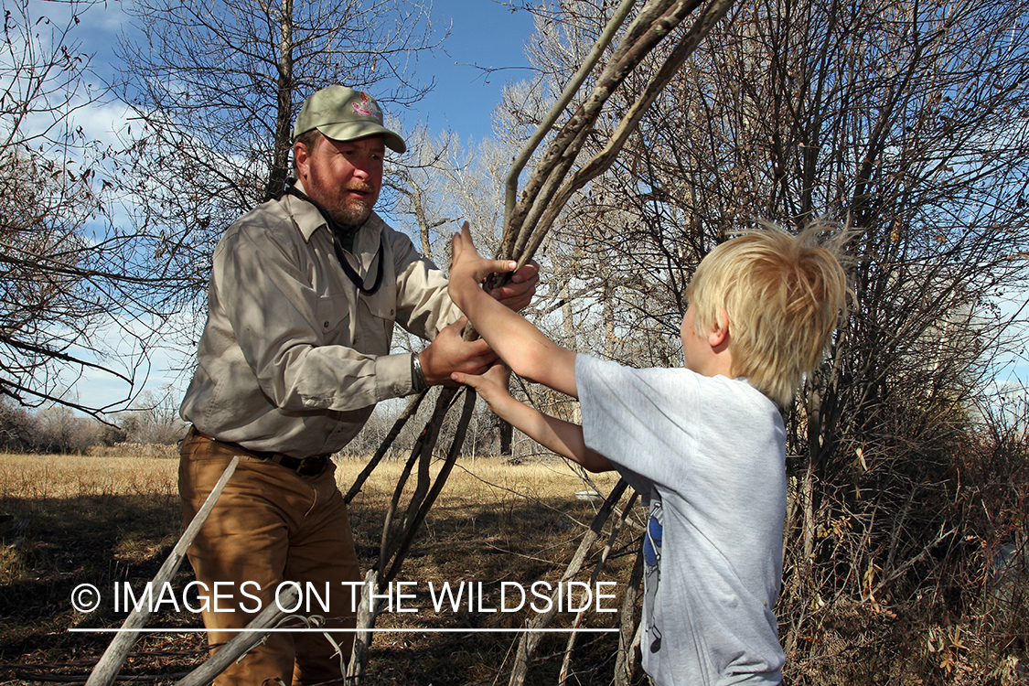 Father and son waterfowl hunters building blind.