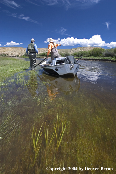 Flyfishermen fishing river (drift boat in foreground).  Summer.