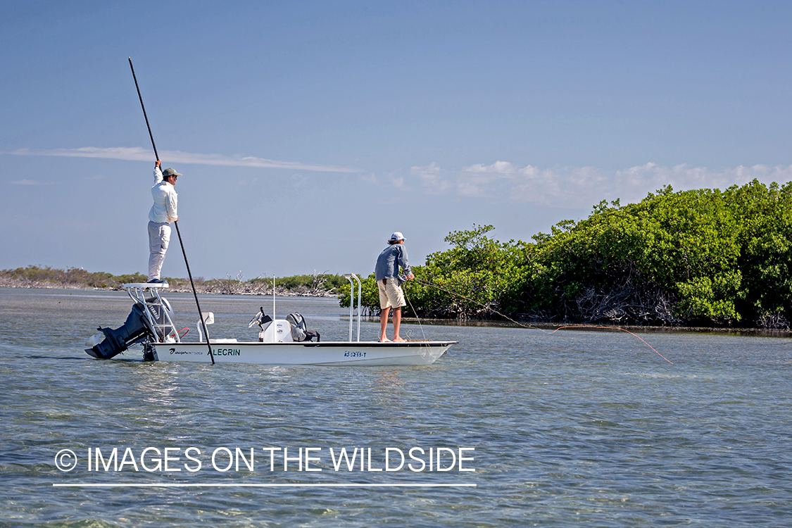 Flyfisherman casting line on flats boat with guide.