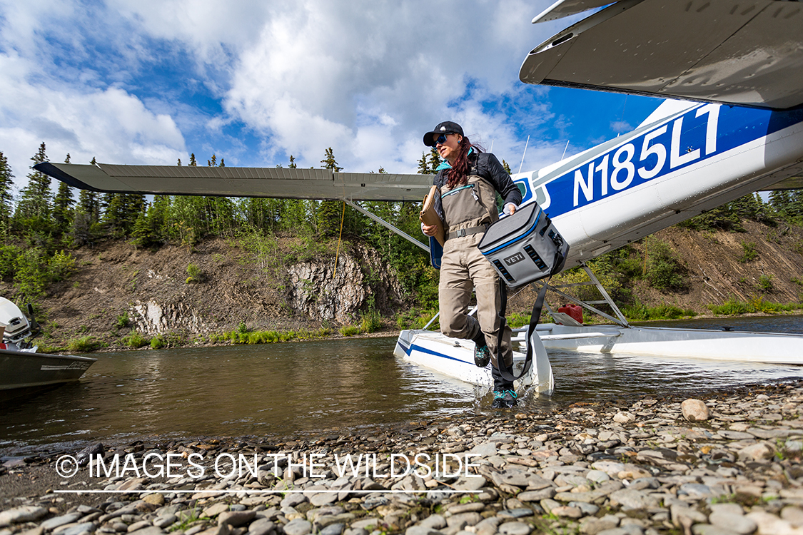 Flyfisher Camille Egdorf stepping out of float plane. 