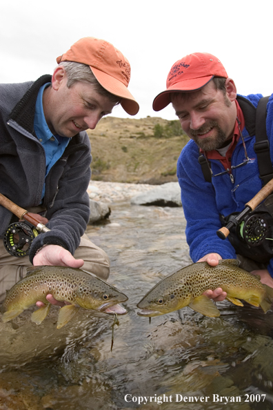 Flyfishermen holding brown trout.