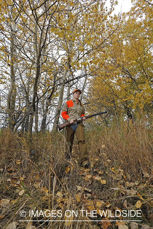 Woman in woodland hunting pheasant.